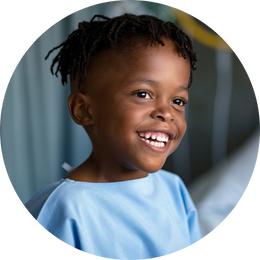 Little boy smiling in hospital gown.